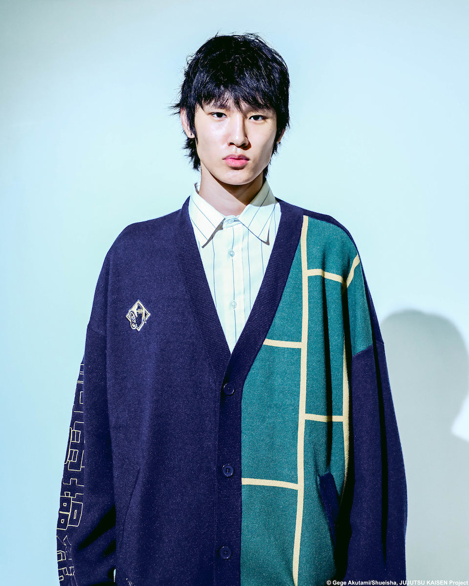 Male model wearing the Jujutsu Kaisen Cursed Spirit Manipulation Cardigan in navy blue with a green and yellow grid pattern on one side, embroidered text reading "We'll meet again in the next world," and Japanese lettering on the sleeve. 